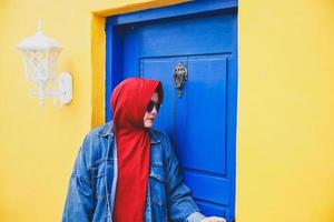 muslimische frau öffnet die blaue holztür auf dem farbenfrohen klassischen gelben haus foto