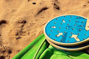 Beachtennisschläger im Sand mit einem grünen Handtuch. horizontales Bild. foto