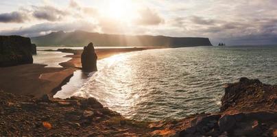 der schwarze sandstrand und die berge reynisfjara vom kap bei sonnenuntergang in island foto