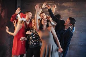 Party mit Freunden. sie lieben weihnachten. Gruppe fröhlicher junger Leute, die Wunderkerzen und Champagnerflöten tragen, die in der Neujahrsparty tanzen und glücklich aussehen. Konzepte zum Zusammengehörigkeitsleben foto