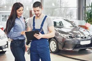 Ein Mechaniker und eine Kundin besprechen Reparaturen an ihrem Fahrzeug foto