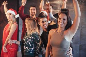 Party mit Freunden. sie lieben weihnachten. Gruppe fröhlicher junger Leute, die Wunderkerzen und Champagnerflöten tragen, die in der Neujahrsparty tanzen und glücklich aussehen. Konzepte zum Zusammengehörigkeitsleben foto