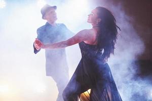 Geschickte Tänzer, die im dunklen Raum unter Konzertlicht und Rauch auftreten. sinnliches Paar, das einen künstlerischen und emotionalen zeitgenössischen Tanz aufführt foto