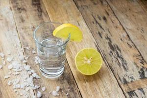 Wodka mit Zitrone auf Holzhintergrund