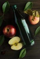 eine Flasche Apfelessig mit frischen Äpfeln und grünen Blättern. foto