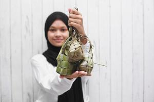 asiatische muslimische frau, die ketupat für eid mubarak-feier zeigt foto