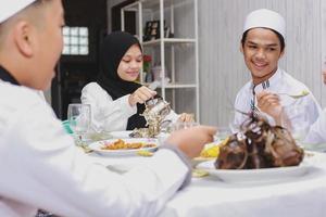 glückliche familie versammelt sich und isst zusammen im speisesaal während der feier von eid mubarak foto