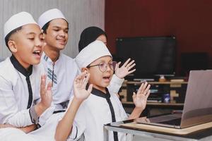 aufregung muslimische familie, die während der eid mubarak-feier videogespräche führt und spaß vor einem laptop hat foto