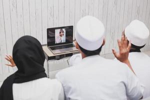 muslimische familie, die einen videoanruf oder zoom mit einem laptop bei der eid mubarak-feier macht foto