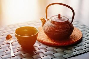 Grüner Tee im Tontopf und leere Tasse auf dem Tisch foto