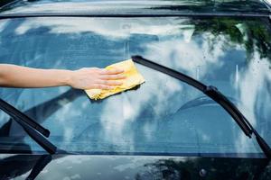 weibliche hand mit gelbem schwamm, der fenster des autos wäscht foto