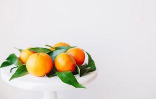 orange mandarinen auf grauem hintergrund im neujahrsdekor mit braunen tannenzapfen und grünen blättern. Weihnachtsdekoration mit Mandarinen. köstliche süße Clementine. foto