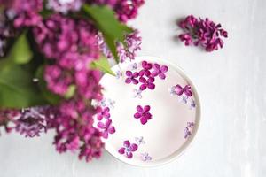 fünfzackige Fliederblüte inmitten von Fliederblüten in einer Tasse mit Wasser. Fliederzweig mit einer Blume mit 5 Blütenblättern. foto