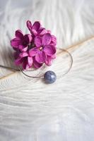 Halskette aus Naturstein mit silbernen Beschlägen mit lila-violett-lila Blüten auf weißer Straußenfeder. silberne Accessoires. foto