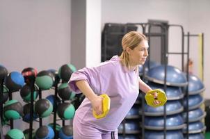 Frau, die leichte Scheiben hält, um Arme und Trizeps im Fitnessstudio zu trainieren. Training und Training zur Gewichtsabnahme und zum Abbau von Körperfett. foto