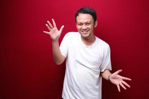 junger asiatischer mann ist glücklich und lächelt mit offener handbewegung foto