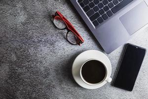 Kaffeetasse auf dem Schreibtisch mit Laptop und Brille foto