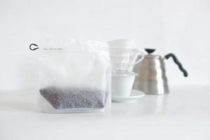 verpackte Kaffeebohnen mit Set Kaffeemaschine auf weißem Hintergrund angeordnet foto