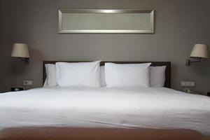 ordentliches weißes Kingsize-Bett im Schlafzimmer foto
