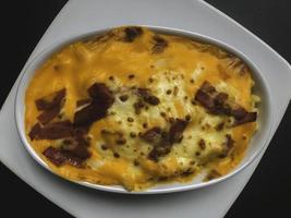 Mac und Käse, Makkaroni-Nudeln im amerikanischen Stil mit käsiger Sauce und knusprigen Semmelbröseln auf dunklem rustikalem Tisch, Draufsicht des Kopierraums foto