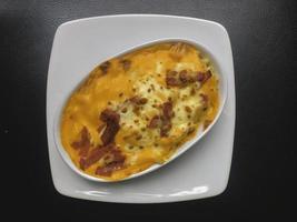 Mac und Käse, Makkaroni-Nudeln im amerikanischen Stil mit käsiger Sauce und knusprigen Semmelbröseln auf dunklem rustikalem Tisch, Draufsicht des Kopierraums foto