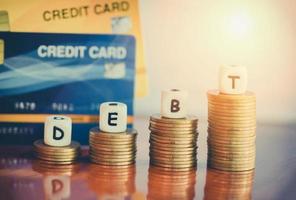 Schuldenkreditkarte auf Münzstapel auf dem Holztisch im Büro - Schuldenmanagementkonzept foto