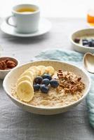 ganze Haferflocken, große Schüssel Haferbrei mit Banane, Beeren, Nüsse zum Frühstück foto