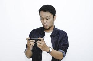 wow gesicht des jungen asiatischen mannes schockiert und überrascht, als er auf dem smartphone spielt. foto