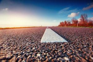 Asphaltstraße am Meer entlang bei Sonnenuntergang foto