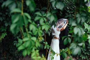 schönes junges Hochzeitspaar, das sich küsst, blonde Braut mit Blume foto