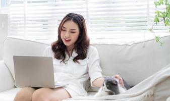 junge asiatische geschäftsfrau, die mit katze arbeitet und spielt foto