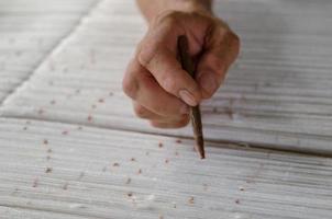 Hand mit einem Bleistift macht Spuren auf dem Teppich. Weben und Herstellung von handgefertigten Teppichen Nahaufnahme foto