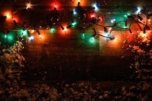 Weihnachtsbeleuchtung auf dunklem Holzbrett foto
