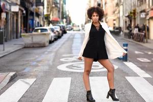 junge schwarze frau mit afrofrisur, die im städtischen hintergrund steht foto