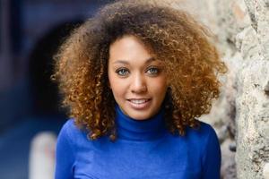 junges Mädchen mit Afro-Frisur, das im städtischen Hintergrund lächelt foto