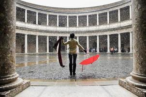 über Frau mit rotem Regenschirm im Palast schneit