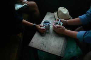 Hände eines Paares, das seinen Morgenkaffee in stimmungsvollem Licht hält foto