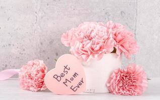 Muttertag handgefertigte Geschenkbox Überraschung wünscht Fotografie - wunderschöne blühende Nelken mit rosa Schleifenbox isoliert auf grauem Tapetendesign, Nahaufnahme, Kopierraum foto