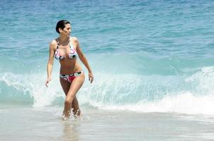 Frau mit schönem Körper in Badebekleidung, die an einem tropischen Strand lächelt. foto