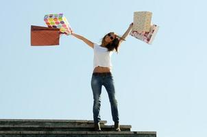 junge Frau, die einige Einkaufstaschen im Freien trägt foto