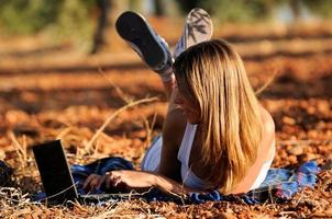 Mädchen mit einem Laptop in einem Feld im Herbst foto