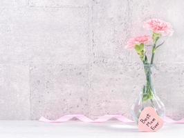 Muttertag handgefertigte Geschenkbox Überraschung wünscht Fotografie - wunderschöne blühende Nelken mit rosa Schleifenbox isoliert auf grauem Tapetendesign, Nahaufnahme, Kopierraum foto