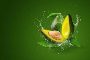 Wasser spritzt auf grüne reife Avocado auf grünem Hintergrund. foto