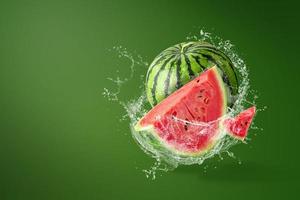 Wasser spritzt auf geschnittene Wassermelone auf grünem Hintergrund foto