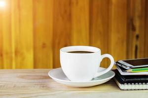 Kaffeetasse, Smartphone und Notizbuch auf Holztischhintergrund foto