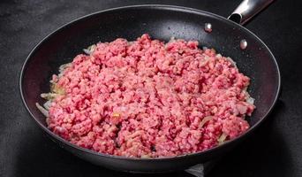 frisches rohes Rinderhackfleisch mit Zwiebeln in einer Pfanne foto