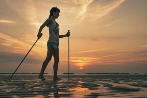 Mädchen üben Nordic Walking am Strand im Morgengrauen foto