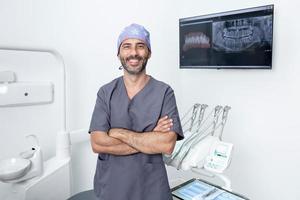 Porträt eines Zahnarztes, der mit verschränkten Armen in einer Klinik steht foto