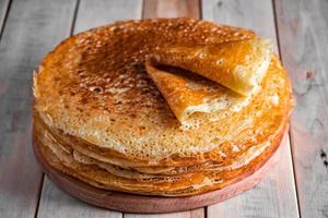 ein Stapel Crêpes auf einem hölzernen Hintergrund. Russisches Essen für den Feiertag Maslenitsa. foto