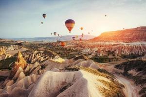 Bunte Heißluftballons, die über das rote Tal in Kappadokien fliegen, foto